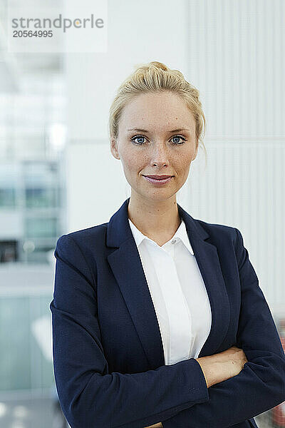 Smiling businesswoman with arms crossed standing in airport