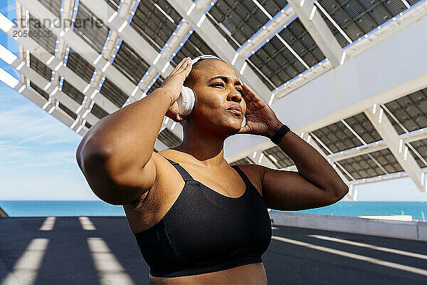 Muscular sporty woman wearing headphones on road