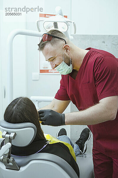 Happy orthodontist examining patient at clinic