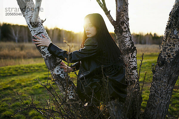 Woman sitting on tree trunk at field