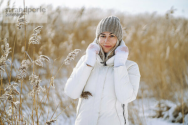 Smiling woman in white warm clothes near plants