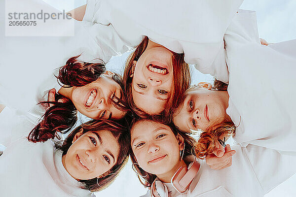 Smiling teenage friends huddling together