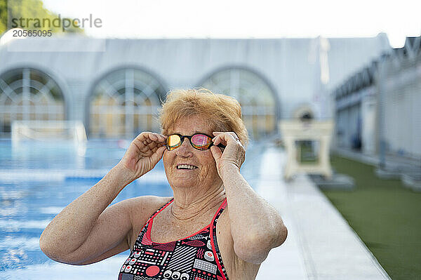 Happy senior woman wearing googles near swimming pool