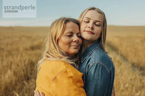 Mother embracing daughter in wheat field