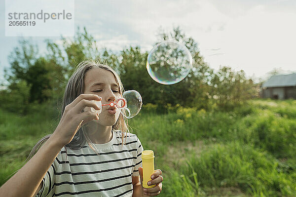 Girl blowing soap bubbles at back yard