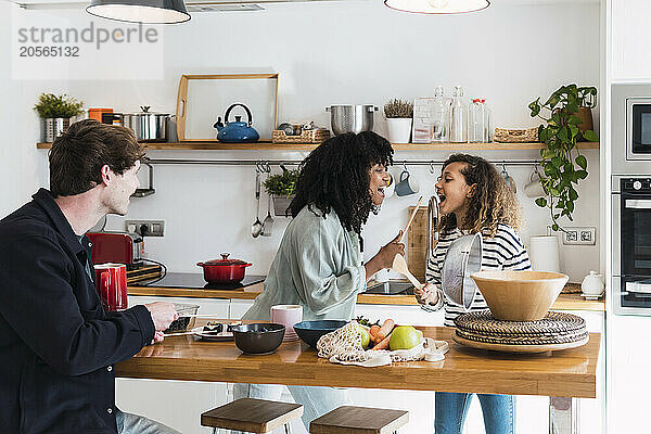 Happy family preparing food together singing and dancing in the kitchen