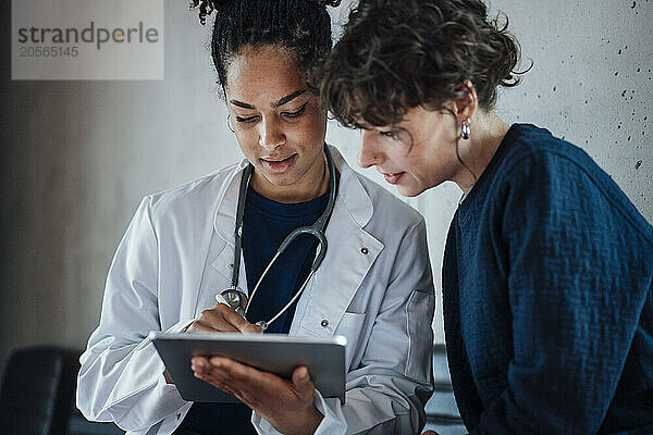 Doctor and patient discussing over tablet PC in hospital