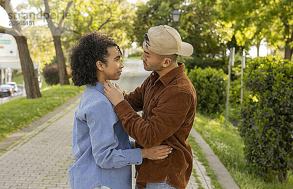 Multiracial couple standing face to face with each other at footpath in park