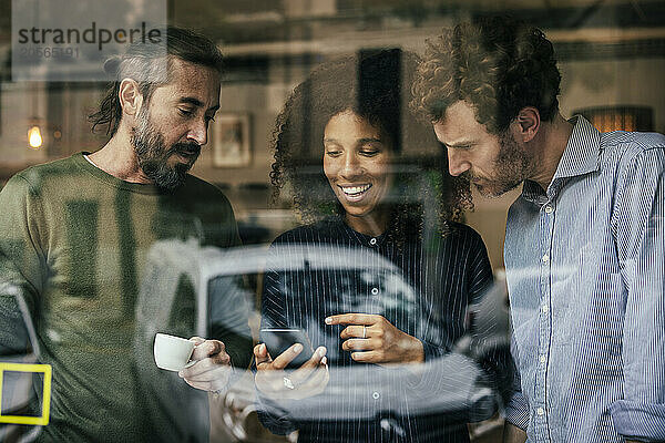 Business colleagues using smartphone in cafe