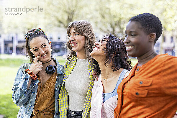 Happy multiracial friends standing side by side at park