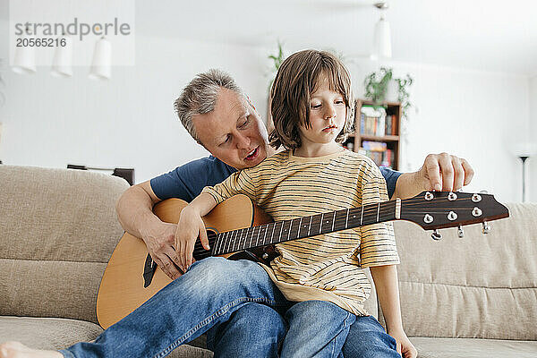 Father teaching guitar to son at home