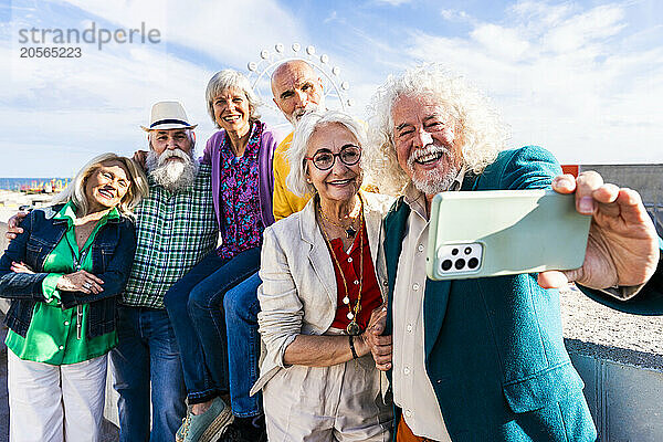 Happy senior man taking selfie with friends on sunny day