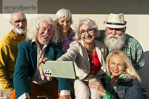 Happy woman taking selfie with retired friends on sunny day