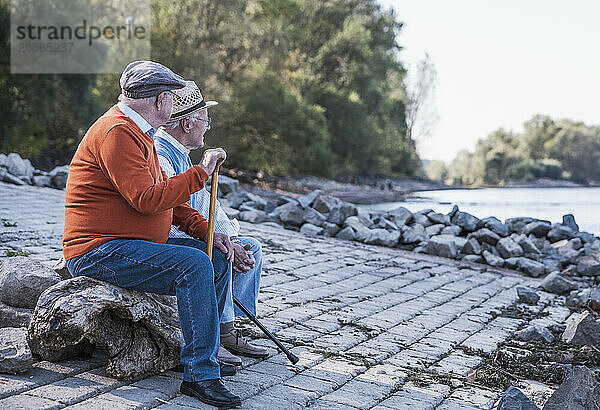 Active senior friends looking at view sitting by riverside