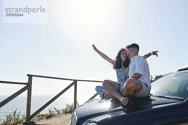 Man sitting with girlfriend on car hood