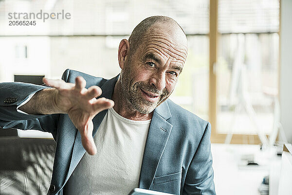 Confident mature businessman with shaved head gesturing at office