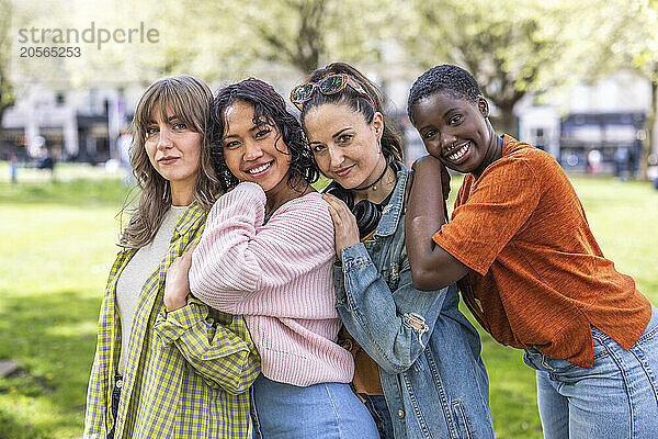 Smiling multiracial women leaning on each other at park