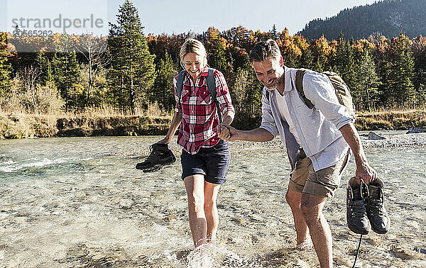 Man holding hand of friend and walking in river