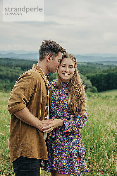 Affectionate young couple spending leisure time in meadow on mountain