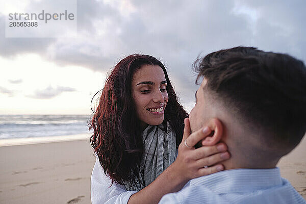 Romantic woman touching boyfriend's face at beach