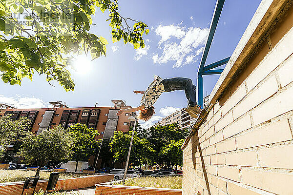 Man doing back flip from wall in park