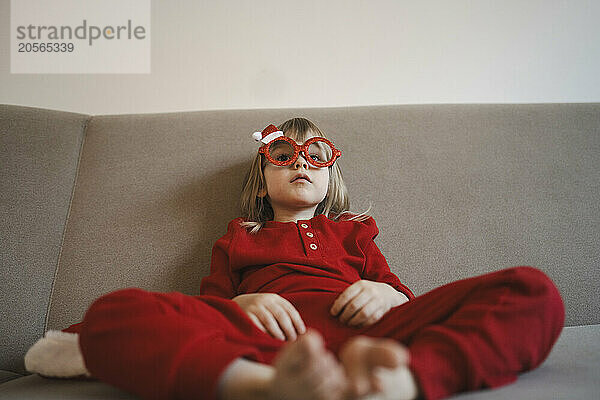 Confident girl with eyeglasses sitting on sofa at home