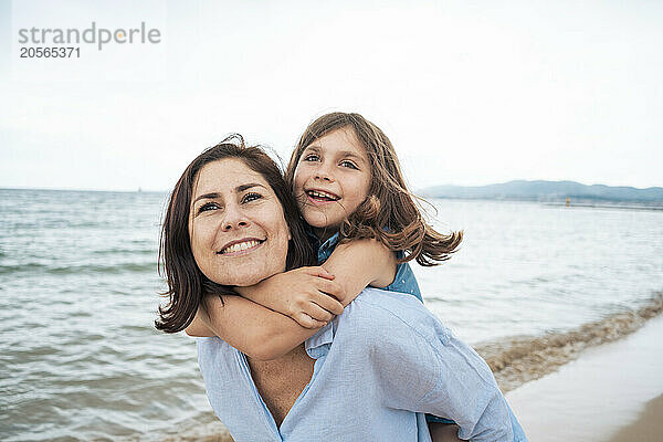 Smiling mother giving piggyback ride to daughter