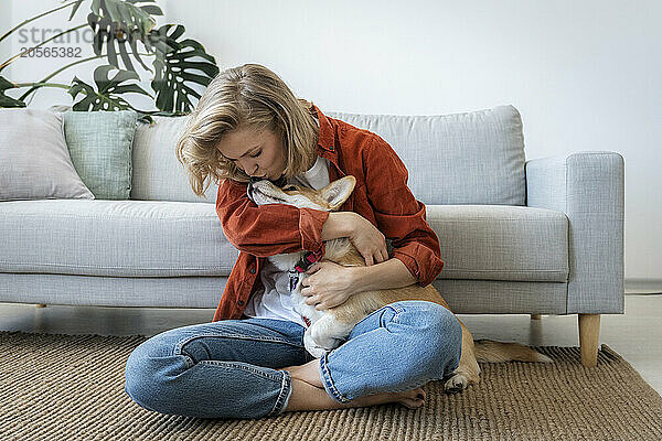 Woman embracing dog sitting on carpet at home