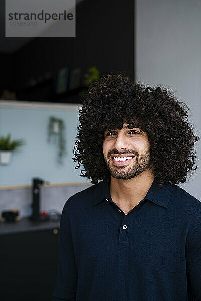 Smiling young handsome businessman with curly hair at office