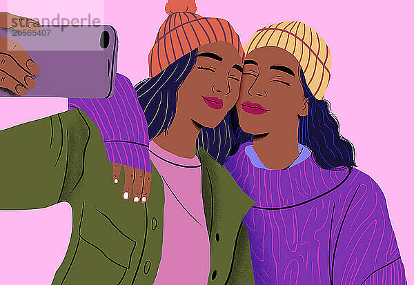 Smiling friends wearing beanies taking selfie in front of pink background