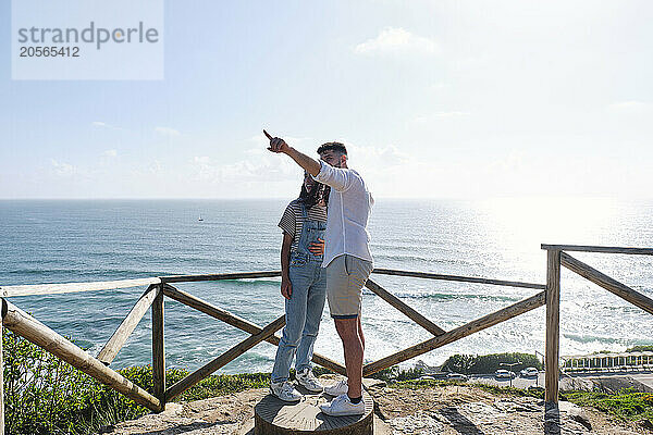 Man pointing by girlfriend standing at observation point