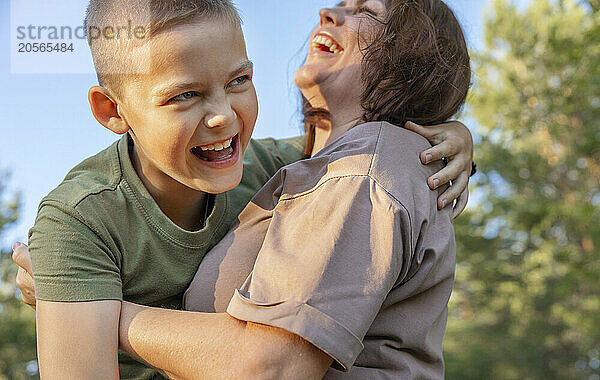 Happy mother and son laughing and playing in the park.