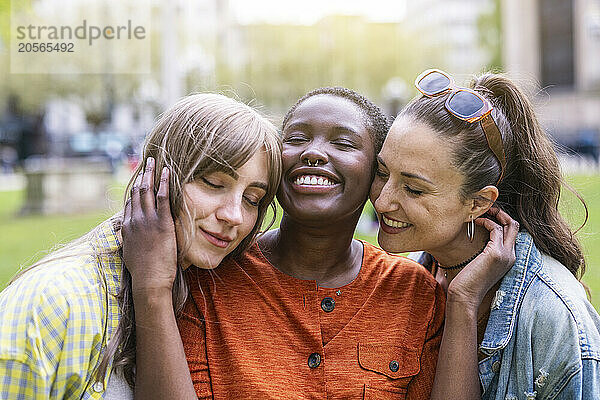 Smiling woman with eyes closed amidst female friends at park