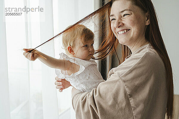 Cute baby girl pulling mother's hair