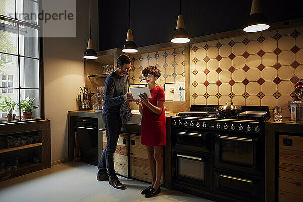 Couple standing and using tablet PC in kitchen at home