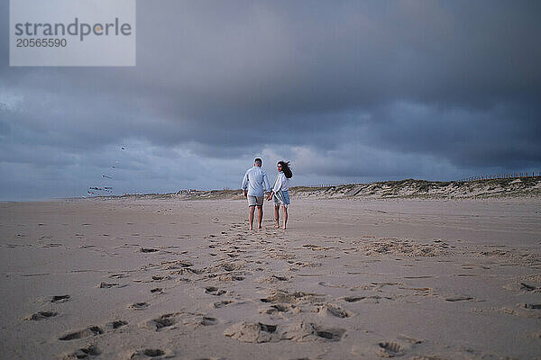 Couple walking at beach under sky