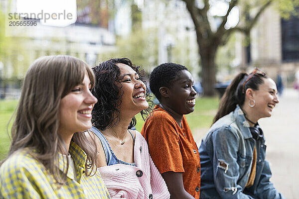 Smiling women sitting side by side in park