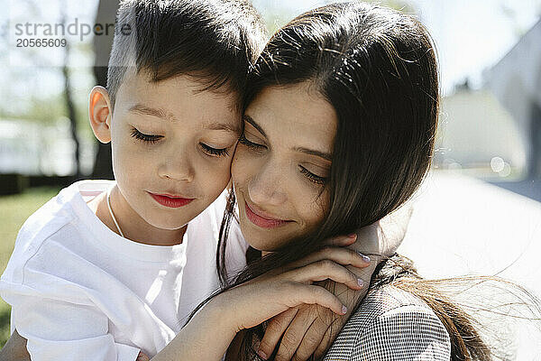 Cute boy with arm around mother