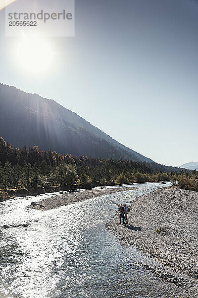 Man and woman near river on sunny day