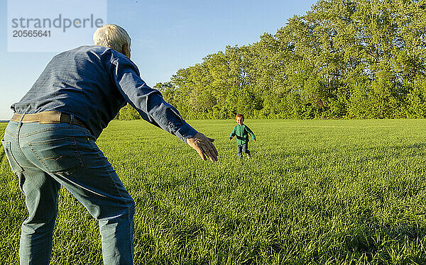 Boy running towards grandfather standing on grass