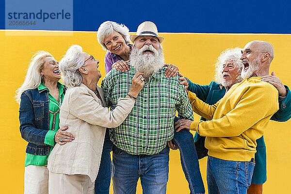 Happy senior men and women playing with friend on footpath