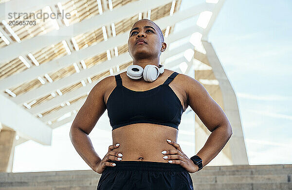 Confident muscular woman standing with arms akimbo on steps