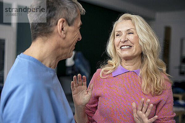 Happy blond woman gesturing and talking to man at home