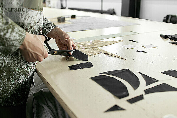 Fashion designer cutting piece of cloth at workshop