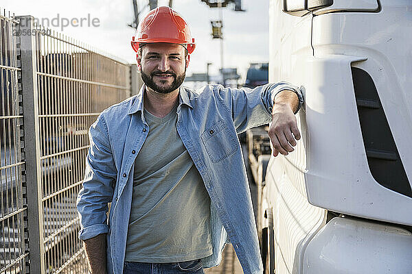 Smiling truck driver standing by truck