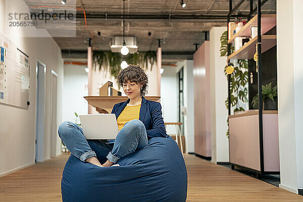 Young businesswoman using laptop on bean bag