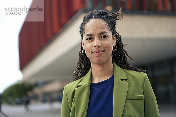 Smiling young beautiful businesswoman standing at office park