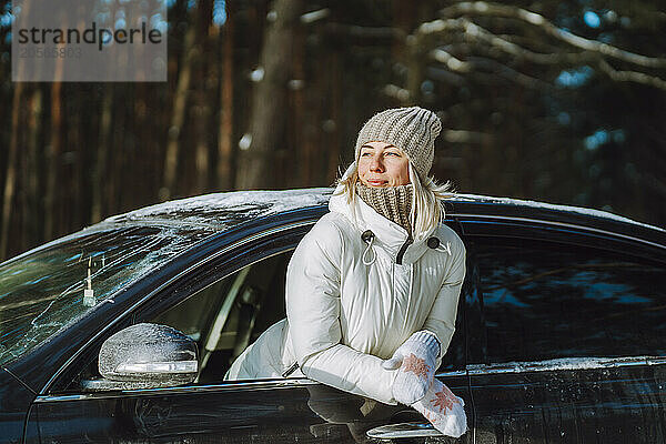 Woman in warm clothes leaning out of car window