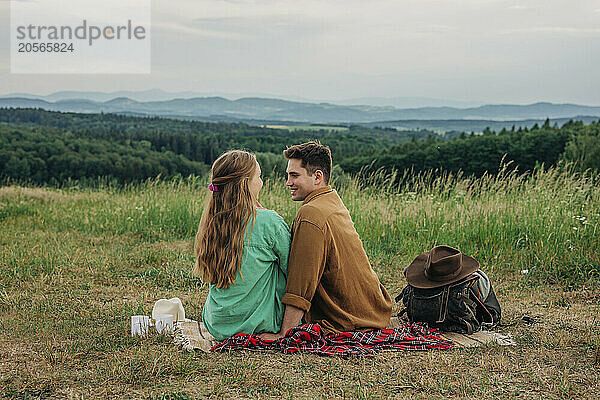 Happy man spending leisure time with girlfriend and sitting on meadow at mountain of Poland