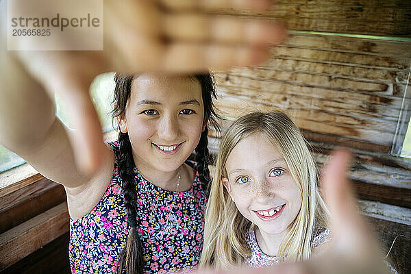 Smiling cute girls making frame with hands